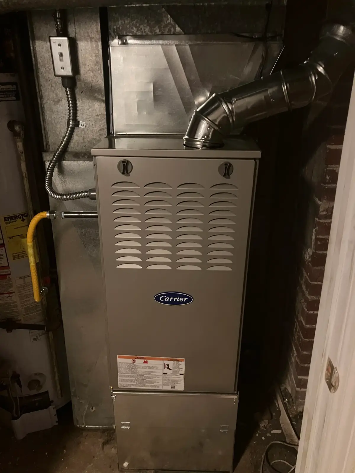 Professional Furnace Installation - Carrier High-Efficiency System Close-up view of professionally installed Carrier furnace showing proper connections, gas line installation, and electrical wiring