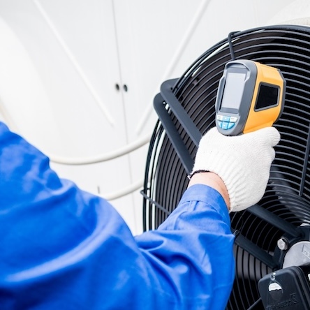 An infrared thermometer held up to a commercial fan.