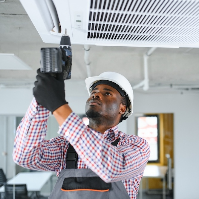 HVAC technician drilling vent into place.