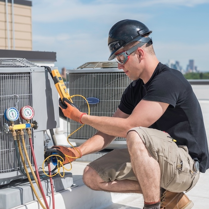 HVAC technician working on an outdoor commercial unit.